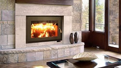 Focus 320 wood-burning fireplace is burning wood, large glass fireplace door above the fireplace opening is a custom fireplace mantel.