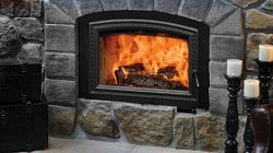 Opel 3 wood burning fireplace with natural grey stone, fire can been seen burning through the large fireplace glass door